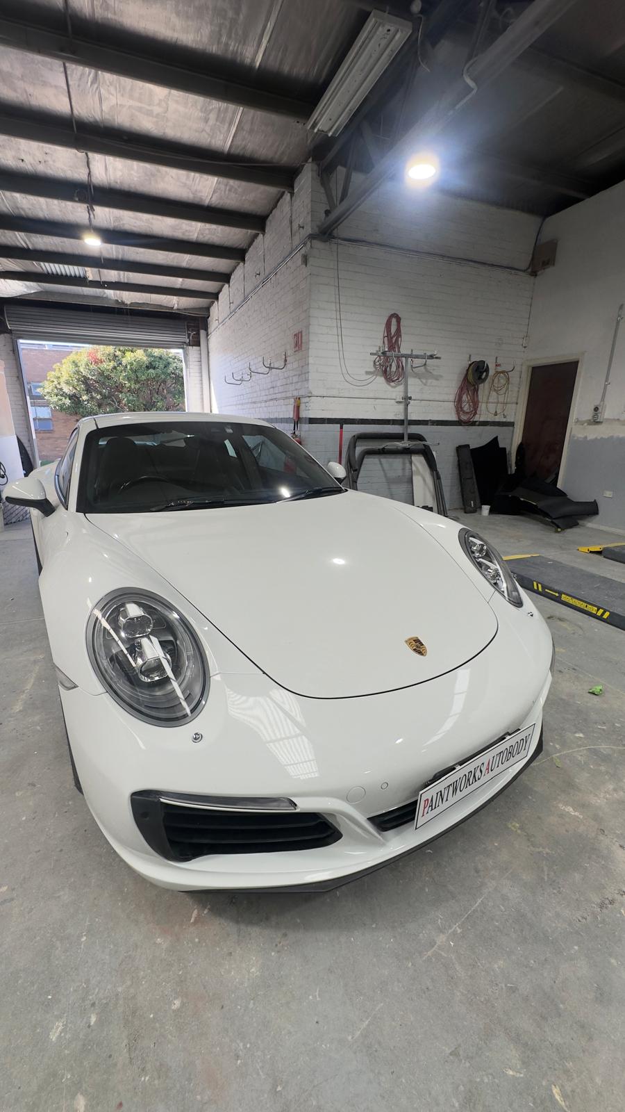 After: white Porsche 911 front bumper restored with factory gloss finish at Paintworks Autobody
